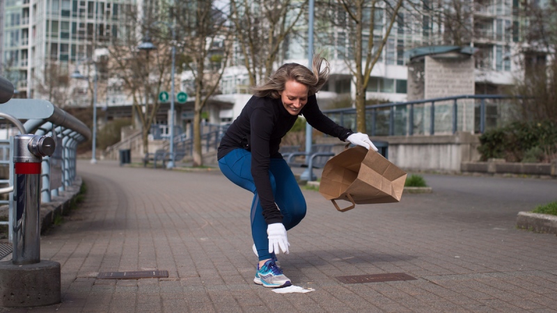Melanie Knight picks up litter while jogging in Vancouver, B.C., on March 21, 2018. (Darryl Dyck / THE CANADIAN PRESS)