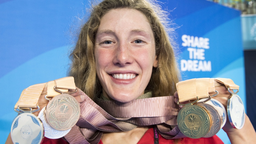 Taylor Ruck holds up her eight swimming medals 