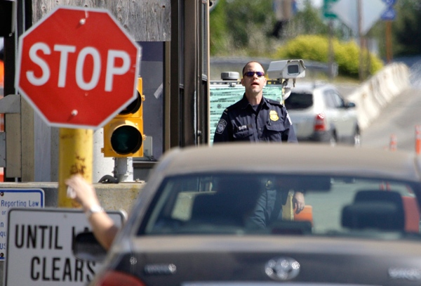 A U.S. Customs and Border Protection officer looks toward a car coming toward him at the border crossing between the U.S. and Canada, in Blaine, Wash. on Saturday, May 30, 2009. (AP / Elaine Thompson)