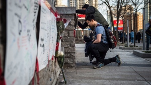 People deliver flowers and write their condolences on a memorial to the victims after a van hit a number of pedestrians on Yonge Street and Finch in Toronto on Monday, April 23, 2018. Ten people died and 15 others were injured when a van mounted a sidewalk and struck multiple pedestrians along a stretch of one of Toronto's busiest streets. THE CANADIAN PRESS/Aaron Vincent Elkaim