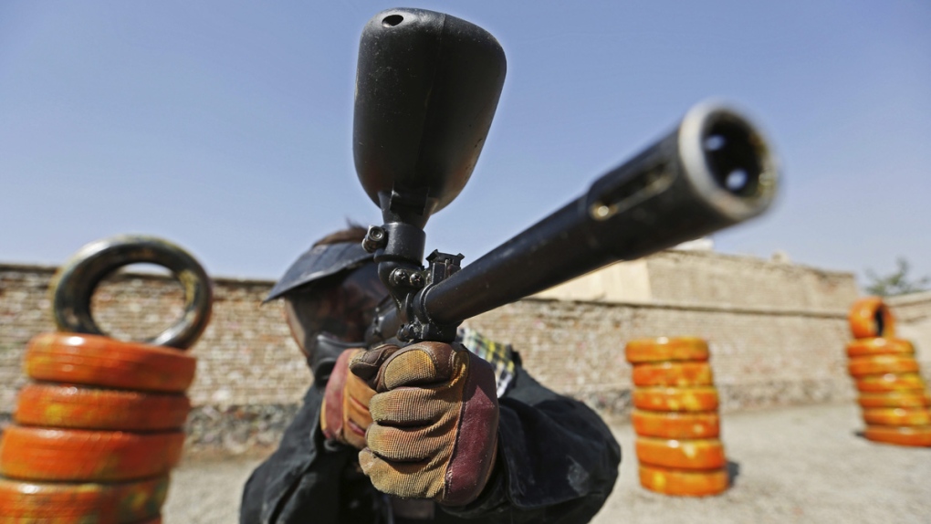 A man holds up his gas-powered paintball gun