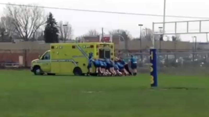 Rugby players from Chateauguay Valley Regional High School push an ambulance off a muddy field on May 2, 2018