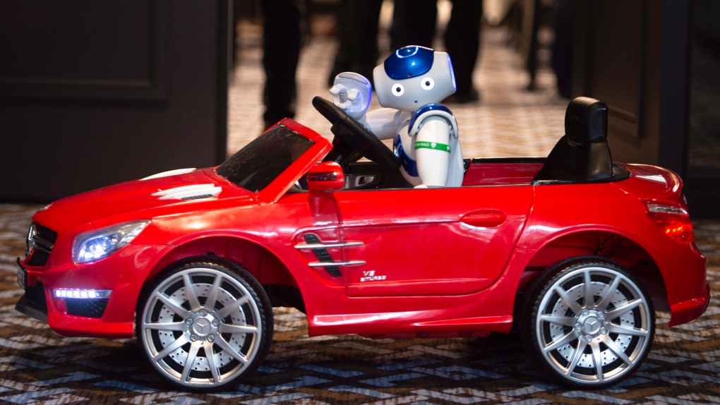 NAO, a humanoid robot, is seen driving a model car