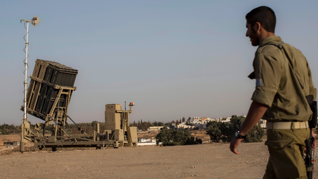 An Israeli soldier walks next to an Iron Dome