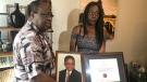 Okwii Modekwe (left) and Chinasa Modekwe (right) are seen holding an image of Ernest Modekwe as a young child and his degree from The University of Toronto inside their home. (CTV News Toronto / Tracy Tong) 