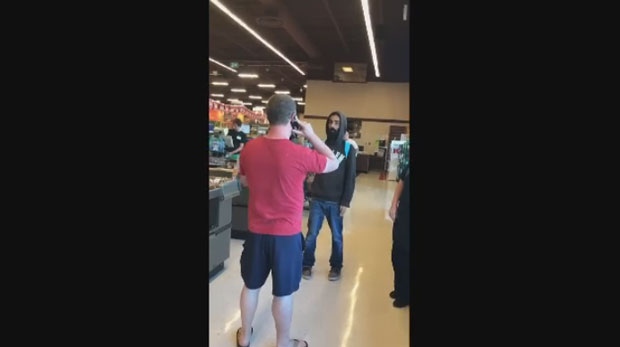 A man is seen in a Facebook video blocking the path of another man while at the checkout of a Sobeys in London, Ont. (Katie Pocasangre Montoya / Facebook)