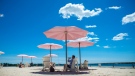 People enjoy the warm weather while protecting themselves from the sun with the pink umbrellas at Sugar Beach, in Toronto on Friday, July 6, 2018. (THE CANADIAN PRESS/Tijana Martin)