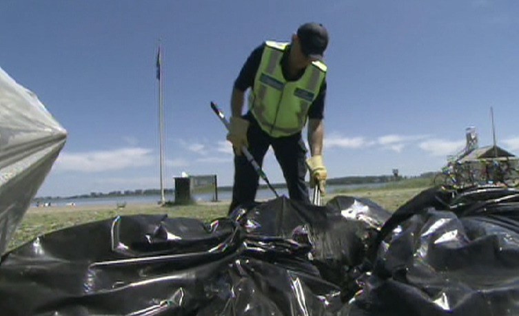 Non-unionized city workers clean up trash that was illegally dumped at Woodbine Beach in downtown Toronto. City officials are searching garbage to link residents to the trash, then charge them.