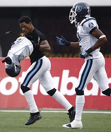Toronto Argonaut Arland Bruce III, left, carries his football gear off the field as teammate Reggie McNeal, right, watches on after celebrating his touch down against the Hamilton Tiger-Cats during first-half CFL action in Hamilton, Ont., on Wednesday, July 1, 2009. (THE CANADIAN PRESS/Nathan Denette)