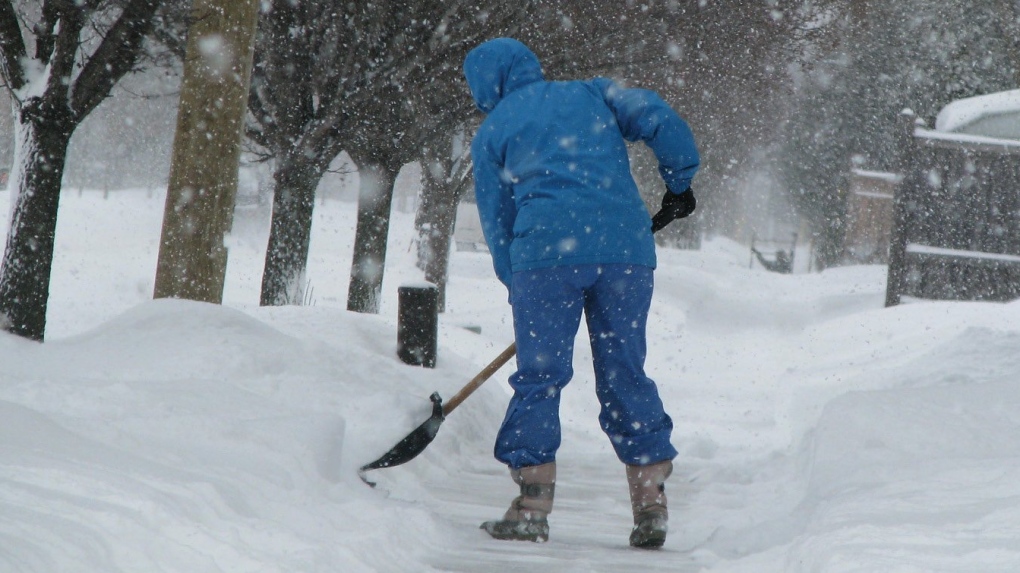 A person shoveling snow from a sidewalk