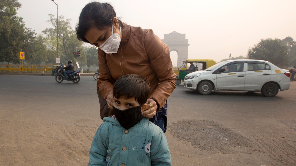 An Indian mother puts a mask to her son