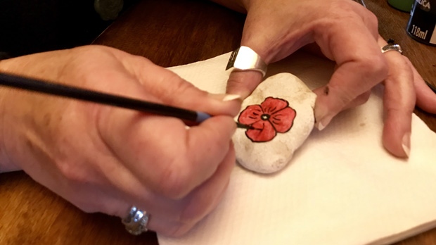 Kat Granda holds up a rock adorned with a freshly-painted poppy. (Jon Hendricks/CTV News.) 