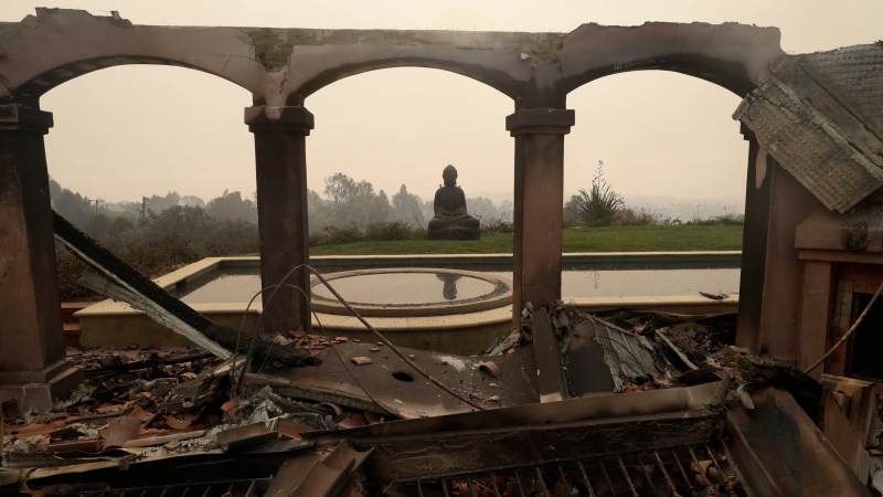 A Buddha statue stands among the damage caused by a wildfire at a home Saturday, Nov. 10, 2018, in Malibu, Calif. (AP Photo/Marcio Jose Sanchez)