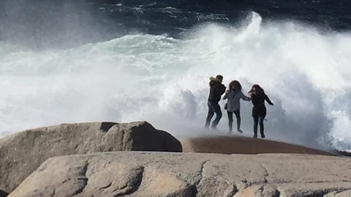This photo, taken Nov. 11, 2018, shows some tourists getting drenched by a wave while walking too far out on the rocks at Peggy's Cove. (Jane MacDonald-O'Connell/Facebook)