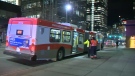 Calgary Transit workers stand next to a bus in the 1000 block of 4 Street SW after it collided with a pedestrian at the intersection of 14 Ave and 4 St SW Wednesday night
