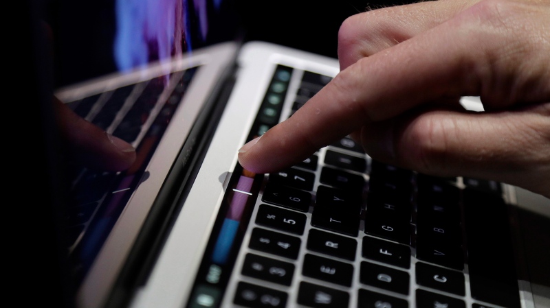In this Oct. 27, 2016, file photo, a guest looks at the Touch Bar on a MacBook computer in Cupertino, Calif. (AP Photo/Marcio Jose Sanchez, File)
