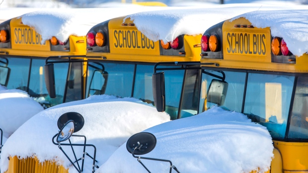 In this file image, school buses sit covered with snow at Smith High School in Greensboro, N.C. on Tuesday, Dec. 11, 2018. (H. Scott Hoffmann/News & Record via AP)