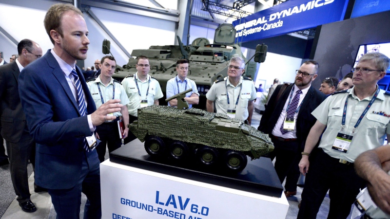 The Ontario-based company that is selling $15-billion worth of armoured vehicles to Saudi Arabia is warning the Liberal government that cancelling the deal will it cost billions of dollars in penalties. A General Dynamics LAV 6.0 is seen behind people as they gather around a scale model of a the same vehicle at the CANSEC trade show in Ottawa on Wednesday, May 30, 2018. (THE CANADIAN PRESS/Justin Tang)