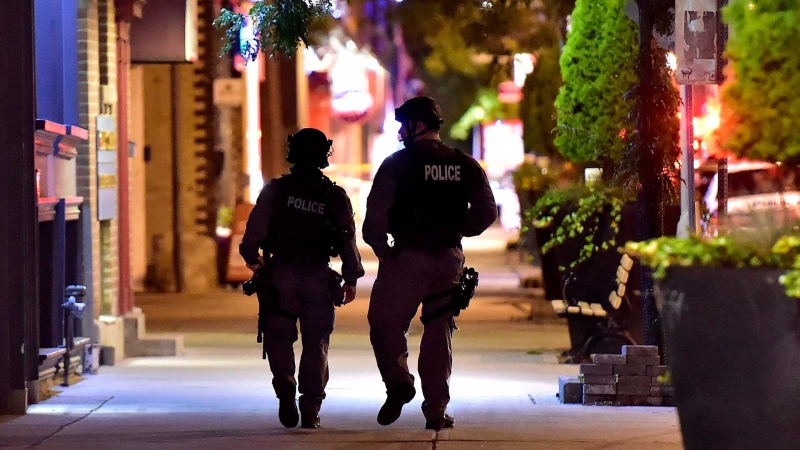 Tactical police officers walk along Danforth Avenue at the scene of a mass casualty incident in Toronto on Monday, July 23, 2018. THE CANADIAN PRESS/Frank Gunn