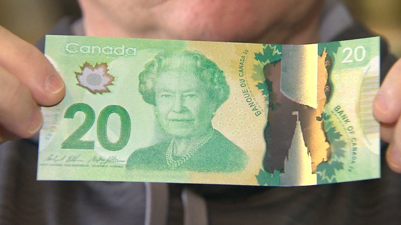 Michael Boddy holds up a fake $20 bill. He says he unwittingly received 63 of the counterfeit banknotes in exchange for a high-end iPhone.