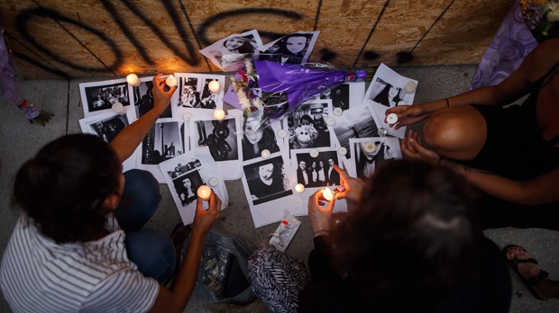 Friends of 18-year-old Danforth shooting victim Reese Fallon, leave candles on pictures of their friend Reese at a makeshift memorial remembering the victims of a shooting on Sunday evening on Danforth, Ave. in Toronto on Monday, July 23, 2018. (THE CANADIAN PRESS/Mark Blinch)