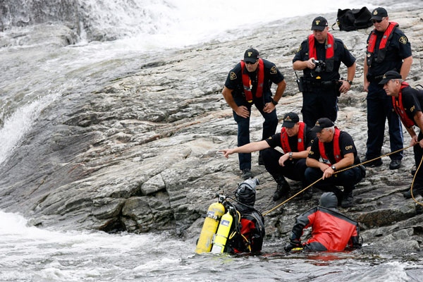 Ontario Provincial Police officers including a diver look into the Moon River Falls, in Ontario, Monday August 3, 2009, as they search for the bodies of three Toronto area residents who went missing in the falls. (Dave Chidley / THE CANADIAN PRESS)
