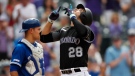 Colorado Rockies' Nolan Arenado, right, gestures as he crosses home plate after hitting a solo home run as Toronto Blue Jays catcher Luke Maile, left, looks on in the seventh inning of a baseball game Sunday, June 2, 2019, in Denver. (AP Photo/David Zalubowski)