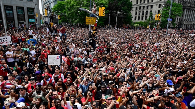Fans line the streets and sit on street signs as they celebrate during the 2019 Toronto Raptors Championship parade in Toronto on Monday, June 17, 2019. THE CANADIAN PRESS/Frank Gunn