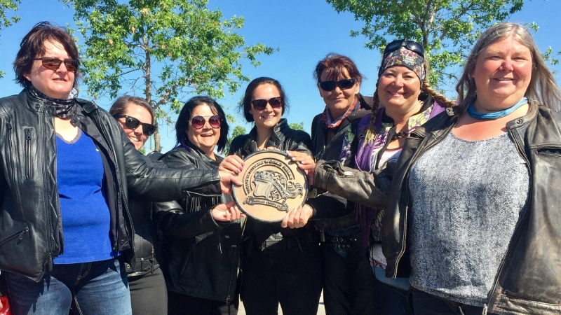 The Saskatchewan motorcycle riders hold a medallion, which will travel across Saskatchewan, and be handed over to a group in Manitoba. (Laura Woodward/CTV Saskatoon)