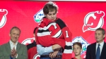 First-overall pick for the New Jersey Devils Jack Hughes puts on his NHL Jersey on his during the first round NHL draft at Rogers Arena in Vancouver, Friday, June, 21, 2019. (THE CANADIAN PRESS/Jonathan Hayward)
