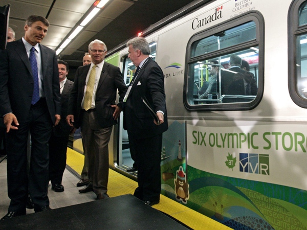Vancouver Mayor Gregor Robinson, left, and British Columbia Premier Gordon Campbell are directed by an aide after riding on the Canada Line rapid transit train's inaugural run from Vancouver International Airport in Richmond, B.C., to downtown Vancouver on Monday August 17, 2009. (THE CANADIAN PRESS/Darryl Dyck)