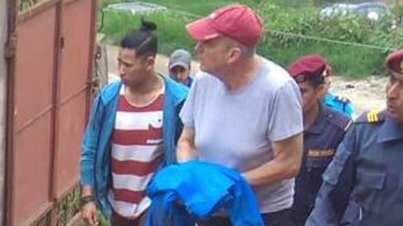 In this Monday, July 8, 2019 photo, Canadian aid worker Peter Dalglish, center wearing red cap, is brought to appear before the Kavre District Court in Nepal. (AP Photo/ Janak Raj Sapkota)