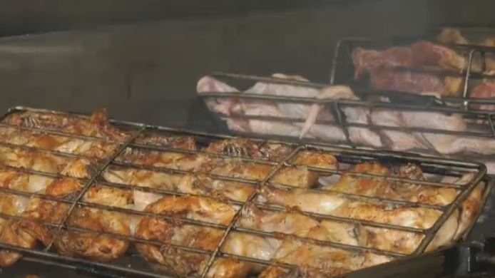 Portuguese chicken cooks on a wood-burning grill