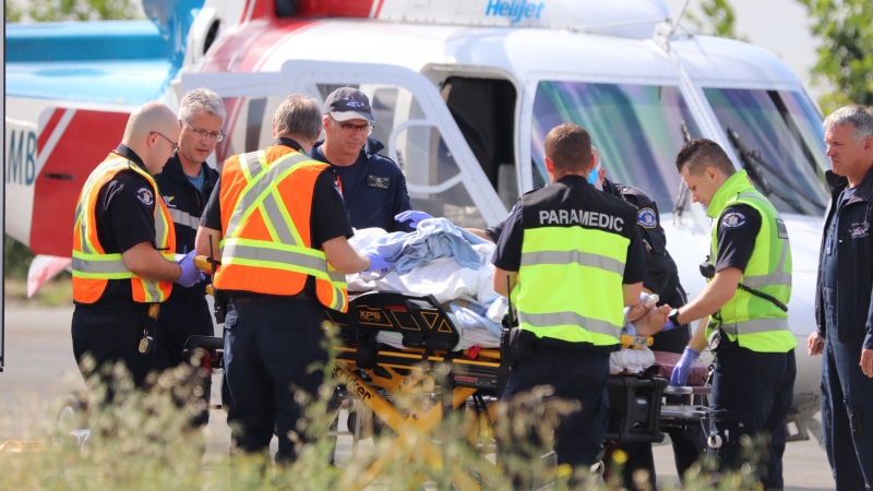 First responders are seen working on a patient after a car went over an embankment in Maple Ridge on July 18, 2019. (Shane MacKichan) 