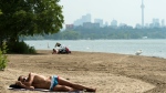 A man sleeps on the sandy beach along Lake Ontario in the extreme heat in Toronto on Friday, July 19, 2019. THE CANADIAN PRESS/Nathan Denette