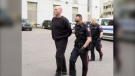 Barry Roach, 48, is led into the Arrest Processing Unit by Calgary Police Service members in June 2019. Roach was charged with second-degree murder in connection with the death of Jeremy Boisseau.