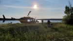 Officers look through a remote lake area alongside a landed helicopter in the Gillam, Man., area in July 28, 2019, police image published to social media. THE CANADIAN PRESS/HO-Twitter, Royal Canadian Mounted Police, @rcmpmb