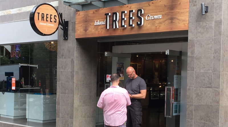 A provincial cannabis enforcement officer (right) stands outside Trees dispensary on Yates Street in downtown Victoria on Aug. 1, 2019. (CTV Vancouver Island)