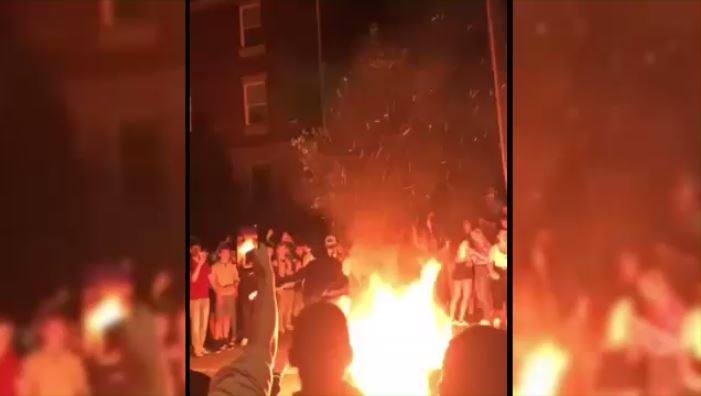 Students jumping over a couch fire during a street party on Ezra Avenue in Waterloo. 