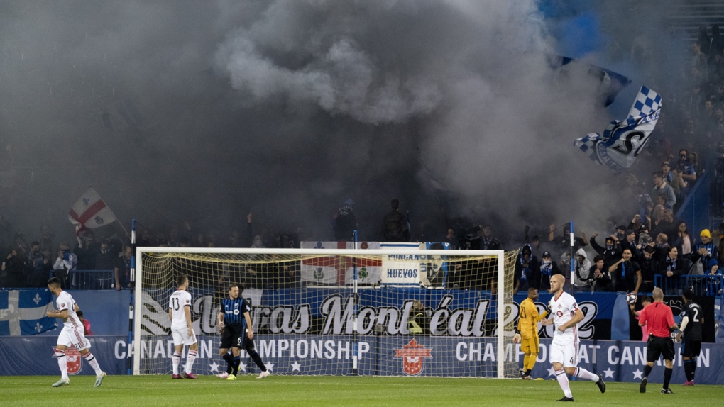 Fans blow smoke from the stands