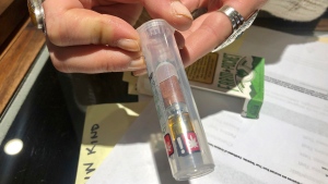 In this photo taken Sept. 20, 2019, Cameron Moore, general manager of Bridge City Collective in Portland, Ore., holds a vape cartridge that's on sale at the dispensary. The company had a 31% drop in sales of vape cartridges that hold the oil that vaporizes when heated. Vaping products are taking a hit as health experts scramble to determine what’s causing a mysterious lung disease. (AP Photo/Gillian Flaccus)