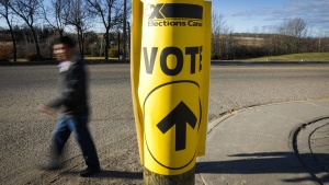 A voter walks past a sign directing voters to a polling station for the Canadian federal election in Cremona, Alta., on Oct. 19, 2015. (THE CANADIAN PRESS / Jeff McIntosh)