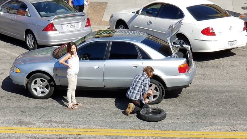 A photo of a homeless man changing a woman's tire in Ogden is capturing the attention of many on Facebook this week, and in the process is helping to send a message. (KSTU, Tribune, Anna Davidson/Facebook)