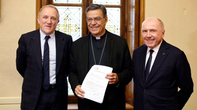 Francois-Henri Pinault, CEO of French luxury group Kering, left, his father Francois Pinault, right, and Archbishop of Paris Michel Aupetit, center, pose after signing an agreement to raise money for the rebuild of Notre-Dame cathedral, in Paris, Tuesday, Oct. 1, 2019. French billionaire Francois Pinault and his son Francois-Henri Pinault have made a 100 million euros ($109 million) donation for the rebuilding of Notre Dame Cathedral. (AP Photo/Thibault Camus)