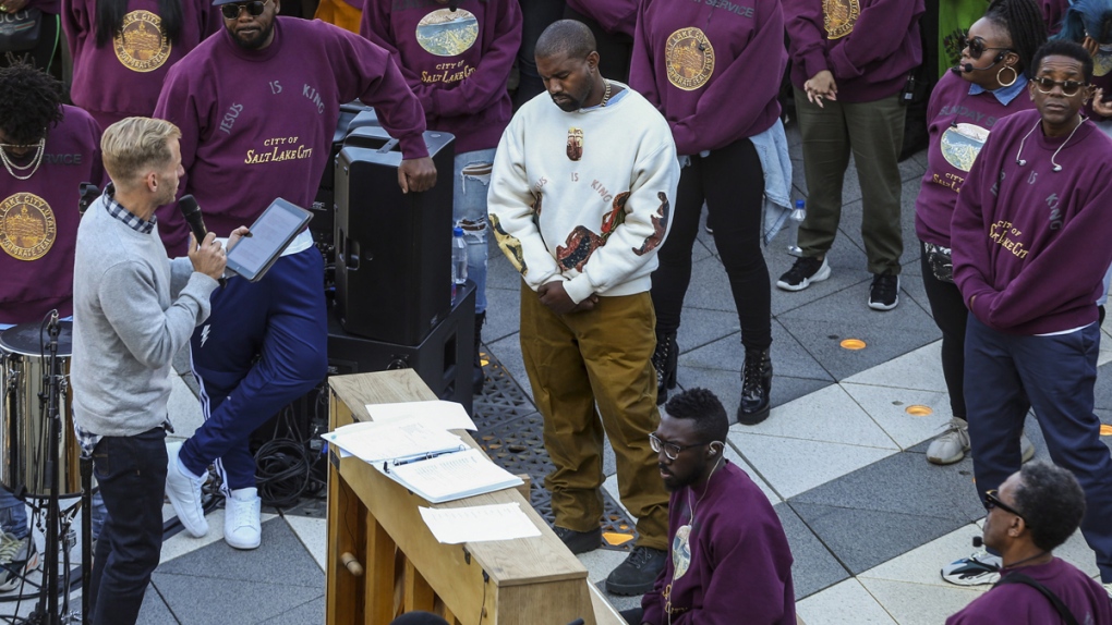 Kanye West, centre, bows his head in prayer