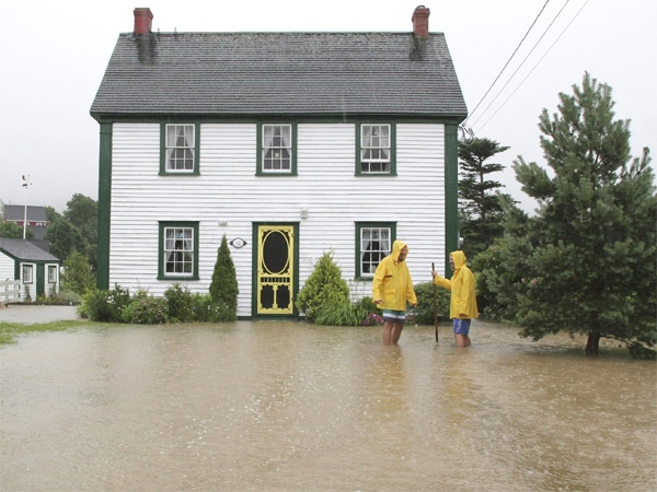 Tom Mitchinson and David Connolly try to keep the flood waters from entering their heritage home in Brigus, Nfld. (CP / St.John's Telegram / Rhonda Hayward)