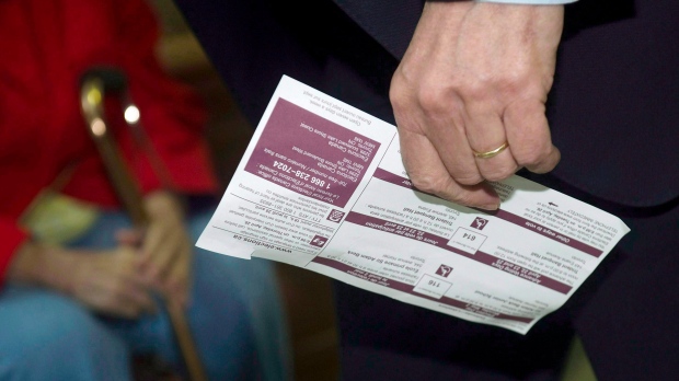 A man carries his voter identification card in this file photo. (The Canadian Press/Nathan Denette)