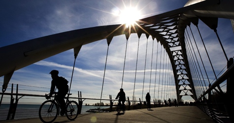People are silhouetted as they ride their bicycles over a bridge during a mild winter day along the lakeshore pathways on the Family Day holiday in Toronto on Monday, Feb. 16, 2009. (Nathan Denette / THE CANADIAN PRESS)    