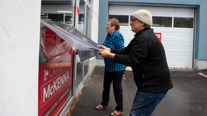 Campaign team members remove a window decal that was defaced with a misogynistic slur on the campaign office of re-elected Liberal MP Catherine McKenna, in Ottawa, on Thursday, Oct. 24, 2019. (THE CANADIAN PRESS/Justin Tang)