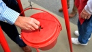 In this Nov. 9, 2018, file photo money gets dropped into the kettle during the annual Salvation Army Kettle campaign kick off in Augusta, Ga. (THE CANADIAN PRESS/Michael Holahan/The Augusta Chronicle via AP)